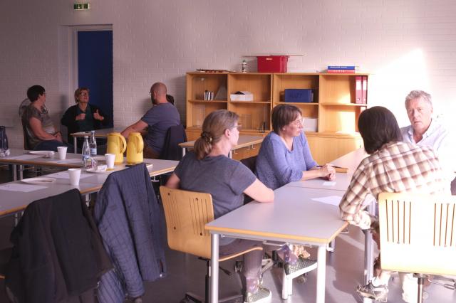 Foto af voksne der sidder og snakker i grupper