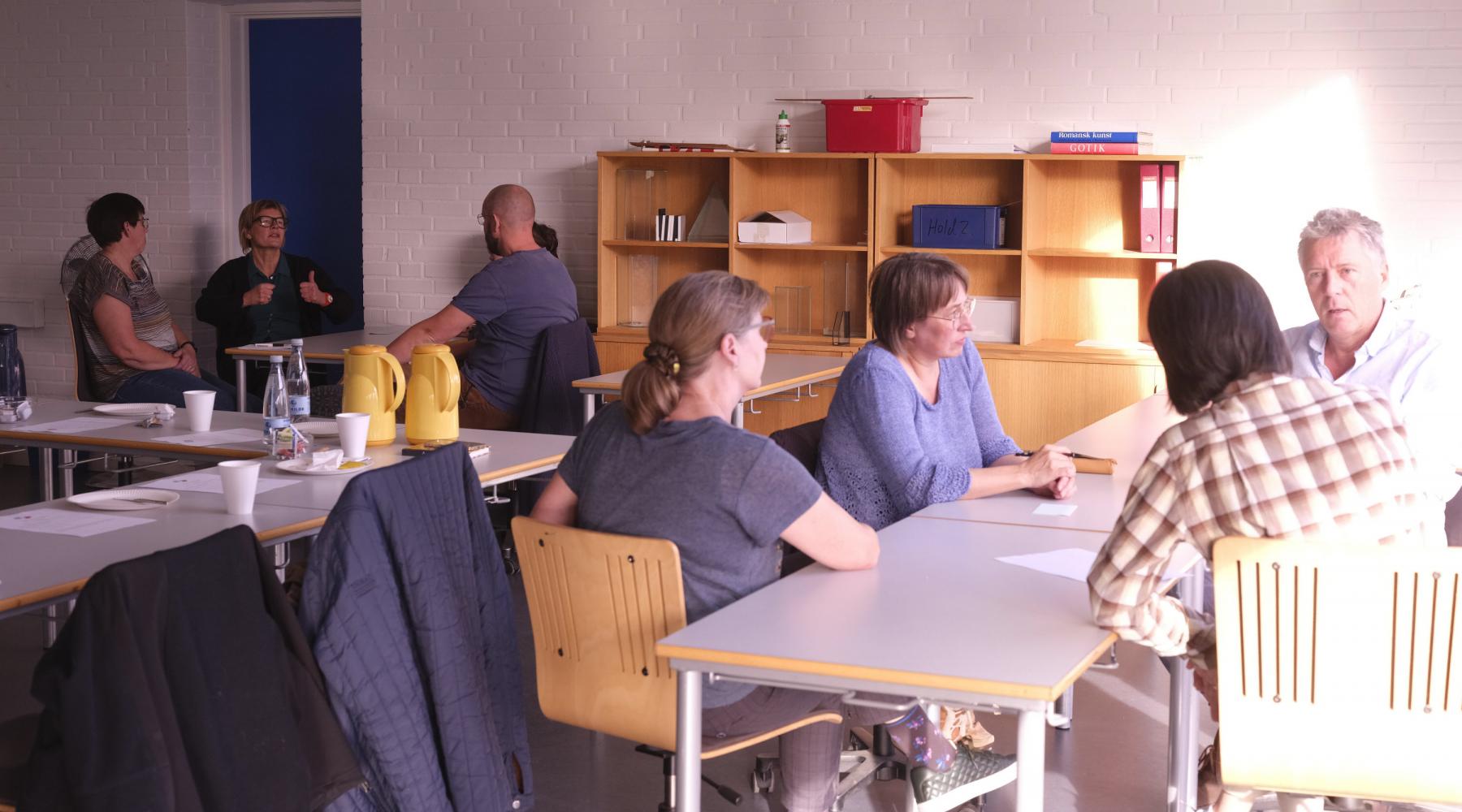 Foto af voksne der sidder og snakker i grupper